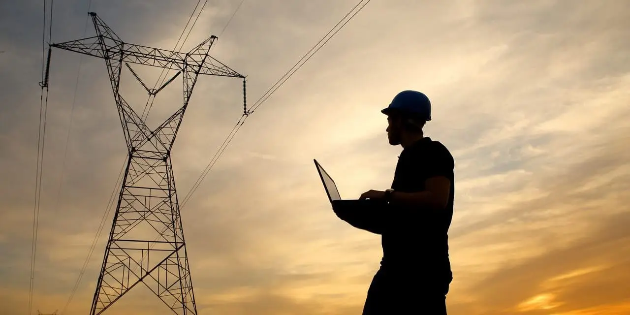 Técnico trabalhando próximo a torres de transmissão